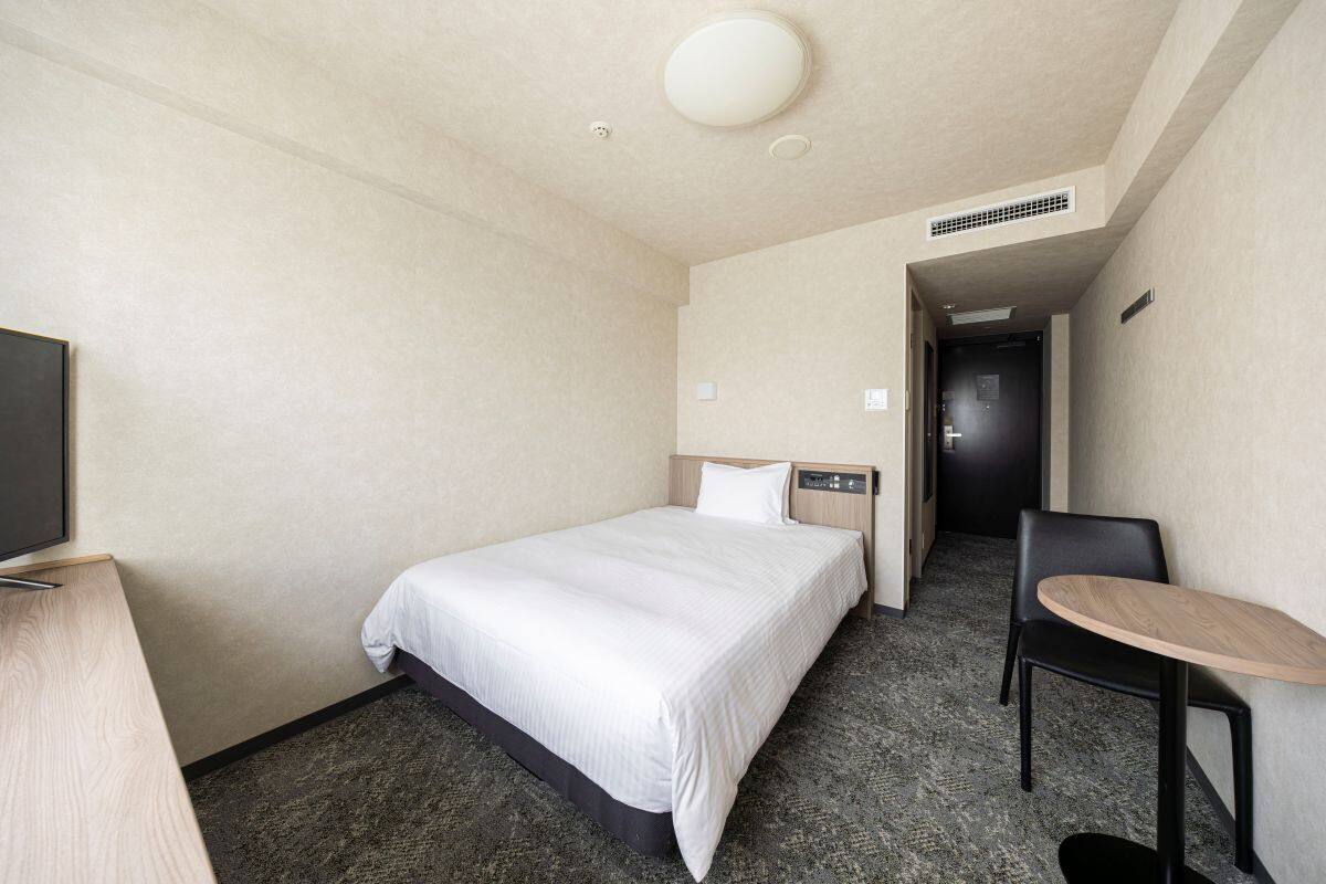 Ein Hotelzimmer mit Bett, Schreibtisch, Stuhl und Fernseher.