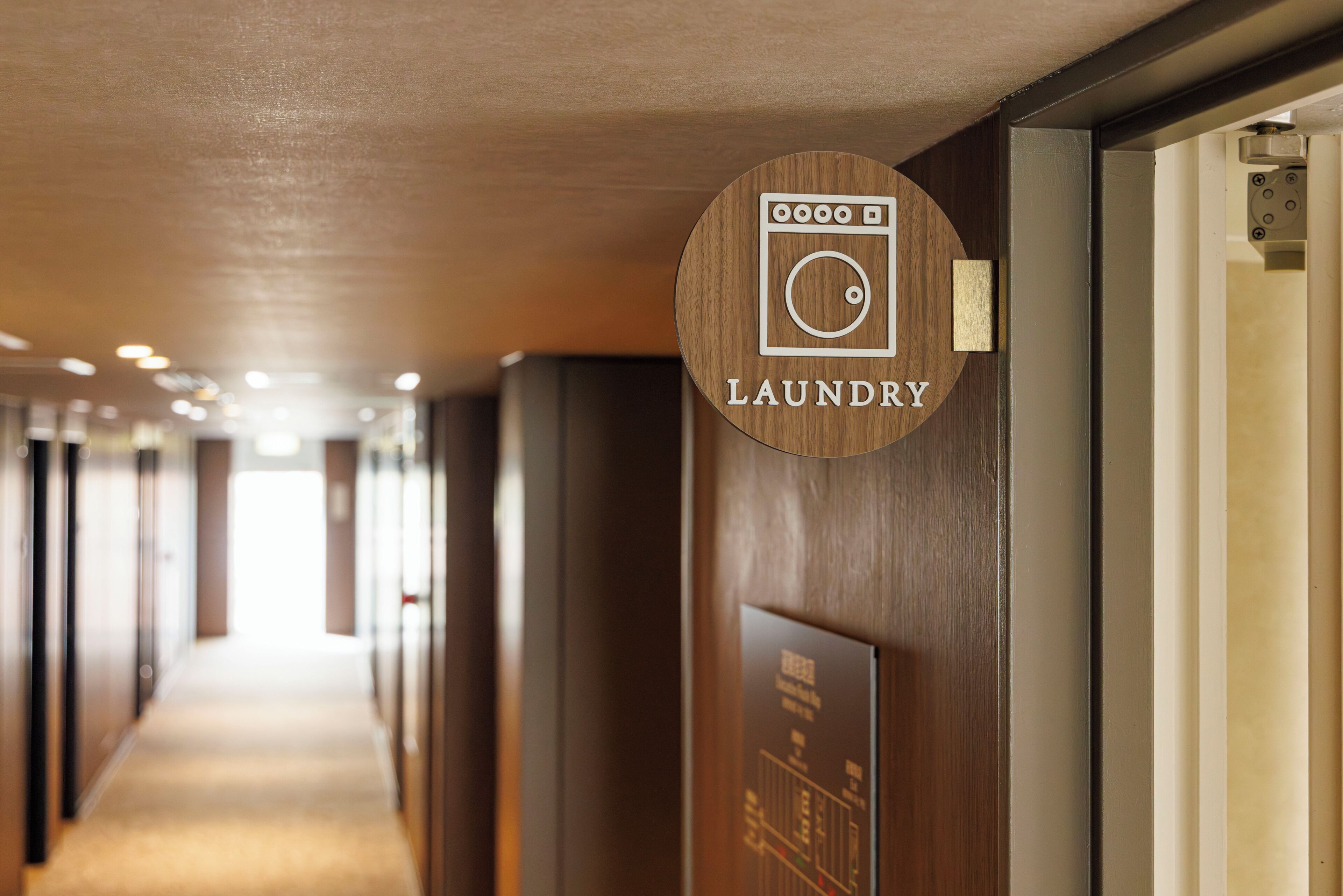 A hotel corridor with a wooden sign indicating the laundry room.