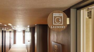 A hotel corridor with a wooden sign indicating the laundry room.