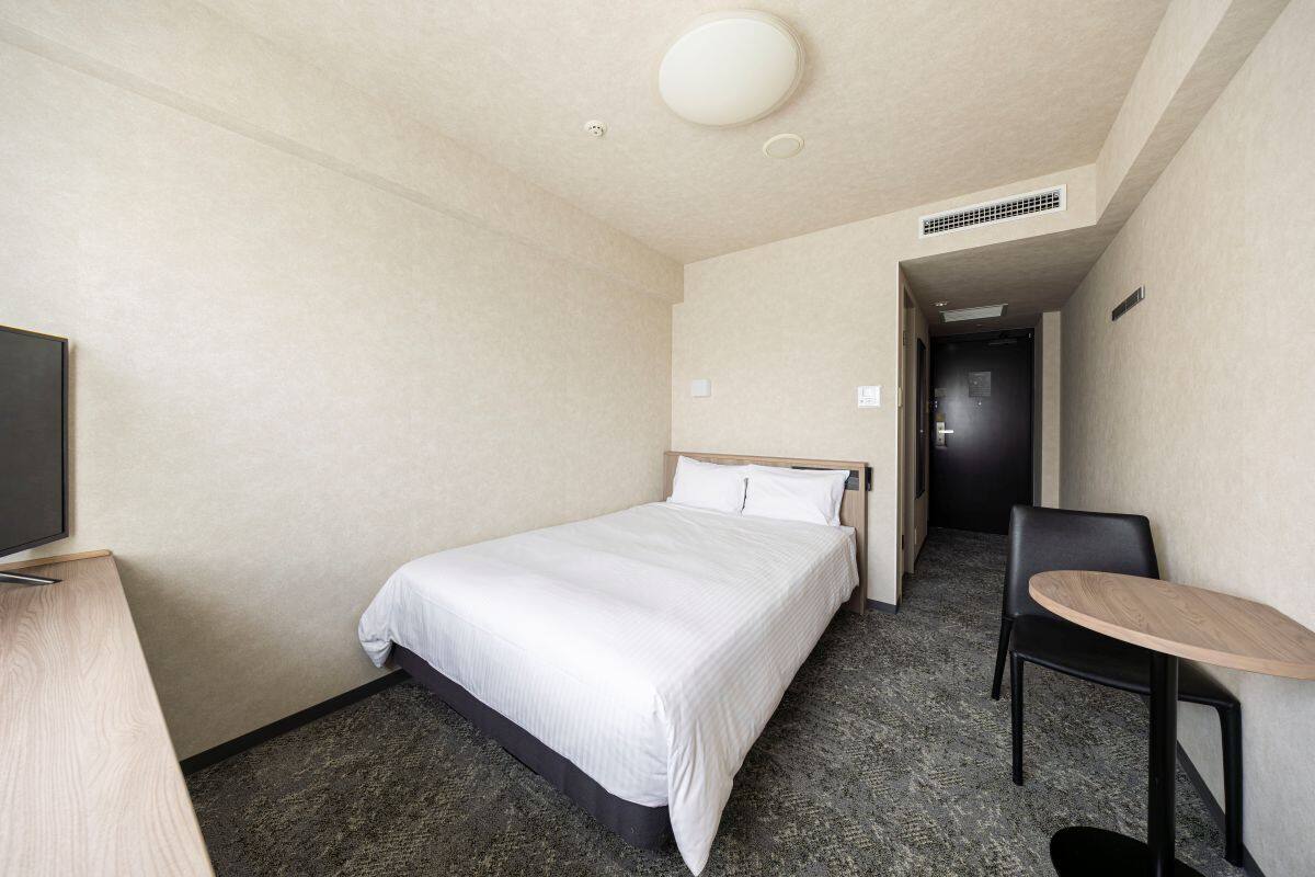 Ein Hotelzimmer mit Bett, Schreibtisch, Stuhl und Fernseher.