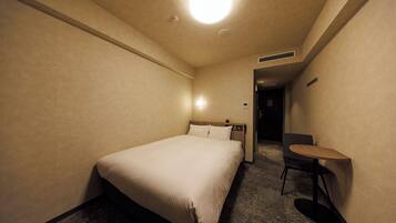 A hotel room with a bed, a small table, and a chair.
