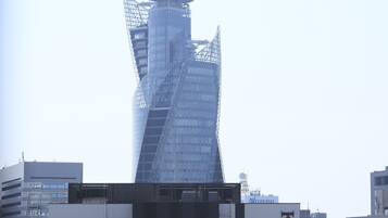 A tall, modern building with a unique twisted design, surrounded by other buildings.