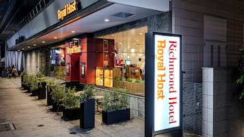 A hotel entrance with a sign for 'Richmond Hotel Royal Host' and a visible outdoor seating area with potted plants.