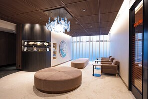 A modern interior with a round seating area, a wall-mounted clock, and a reception desk. - Richmond Hotel Nagoya Nayabashi (Nagoya)