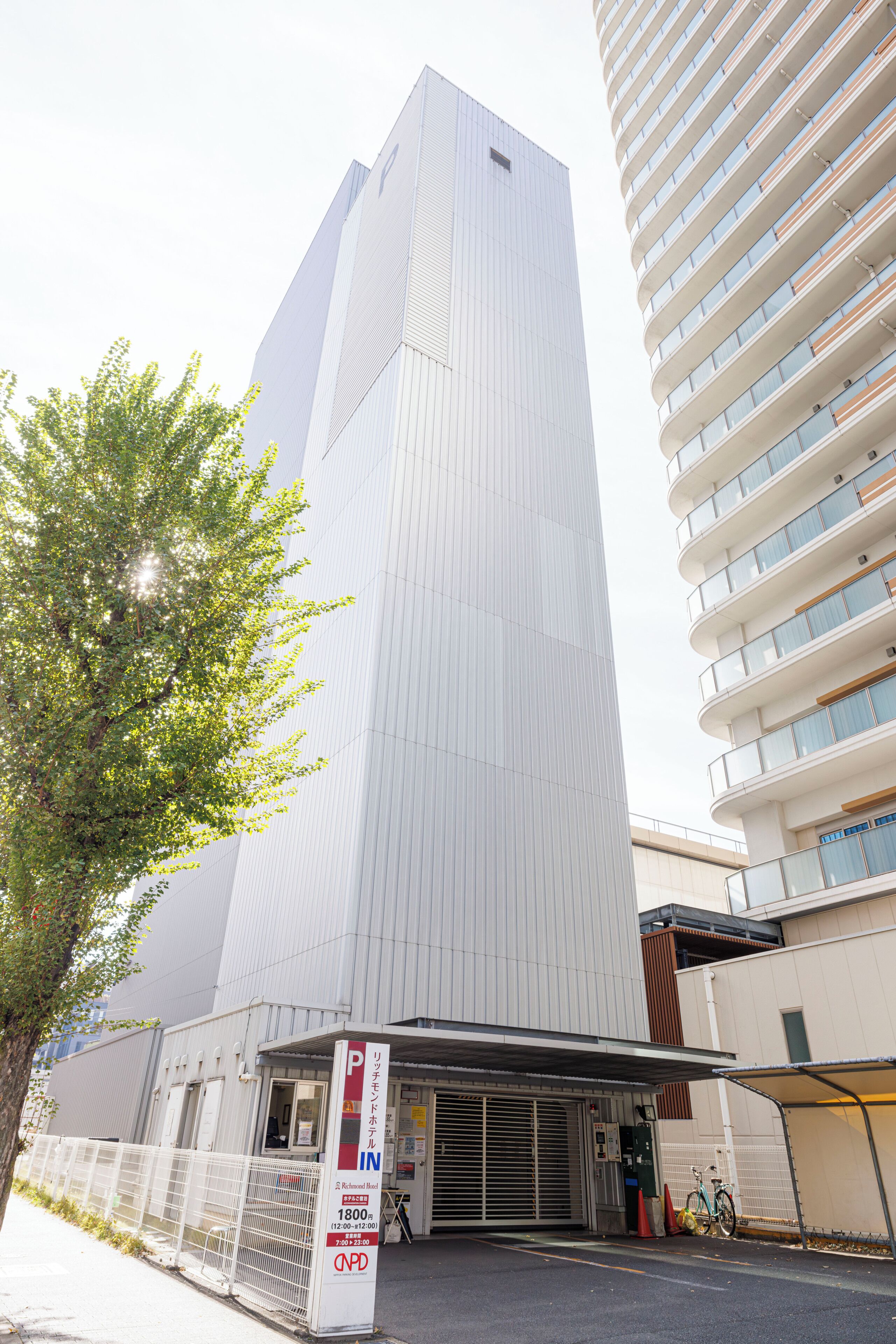 A modern building with a prominent entrance, a parking sign, and a bicycle parked outside.