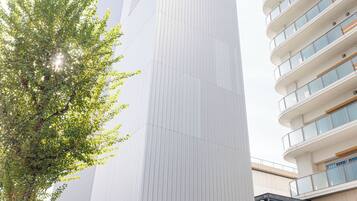 A modern building with a prominent entrance, a parking sign, and a bicycle parked outside.
