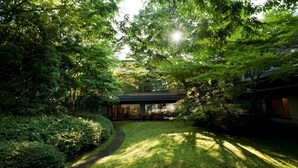 A modern building with a glass facade, surrounded by lush greenery and a well-maintained lawn. - Ranzan Hotel (Kyoto)