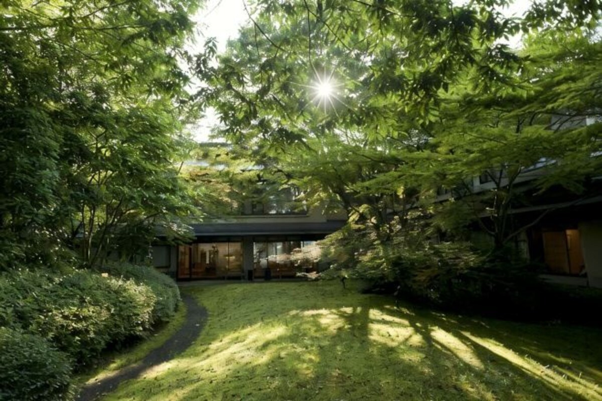 Una casa tradicional japonesa rodeada de exuberante vegetación y un jardín cuidado.