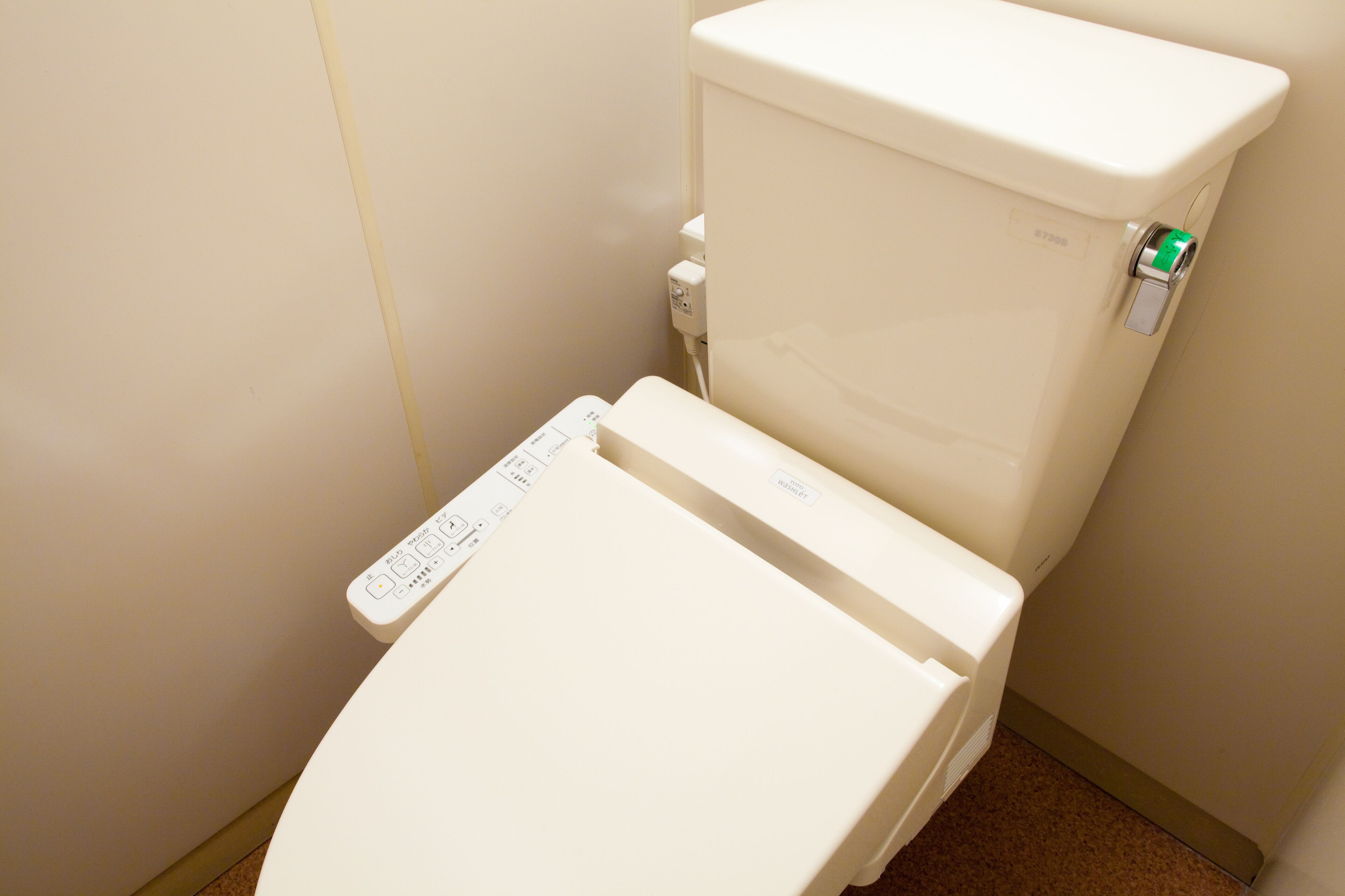 A toilet with a control panel and a visible water tank.