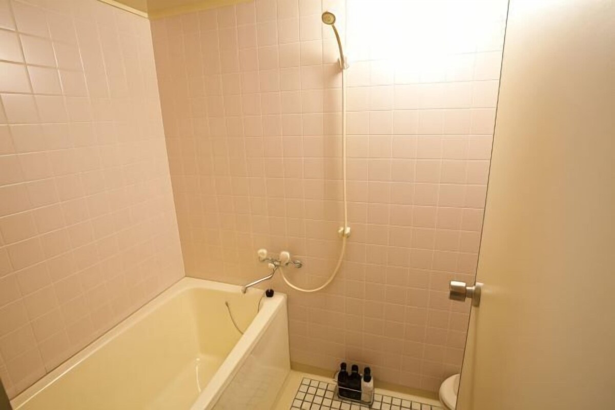 A small, tiled bathroom with a bathtub, a shower, and a toilet.