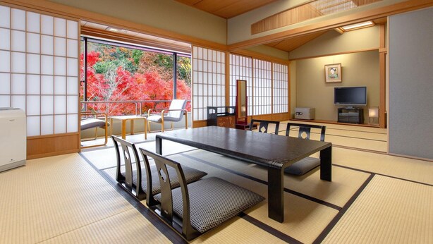 A traditional Japanese room with tatami flooring, a low table, and a television. - Ranzan Hotel (Kyoto)