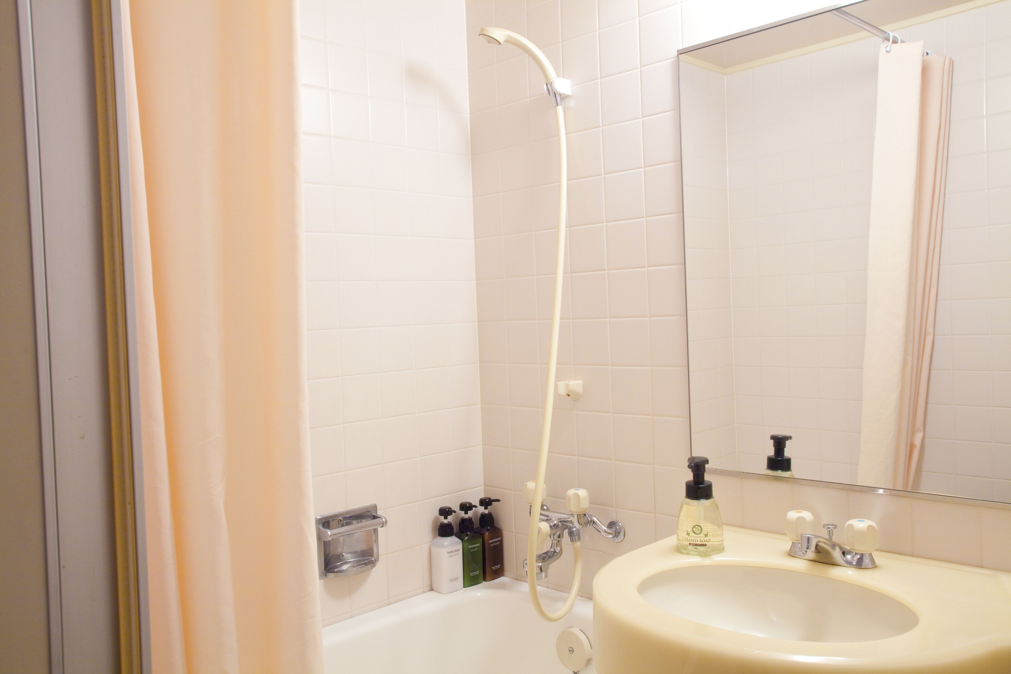 A bathroom with a bathtub, a sink, and a mirror.