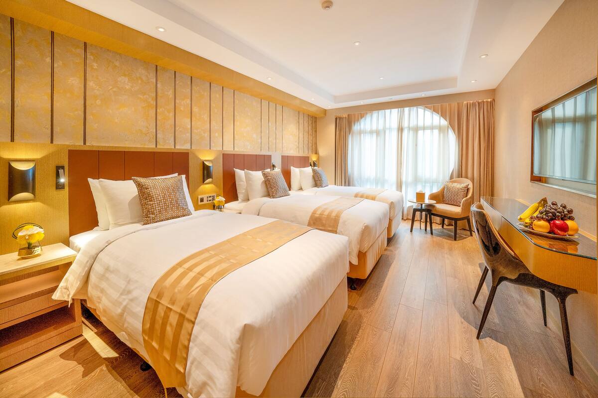 A hotel room with two beds, a desk, and a chair.