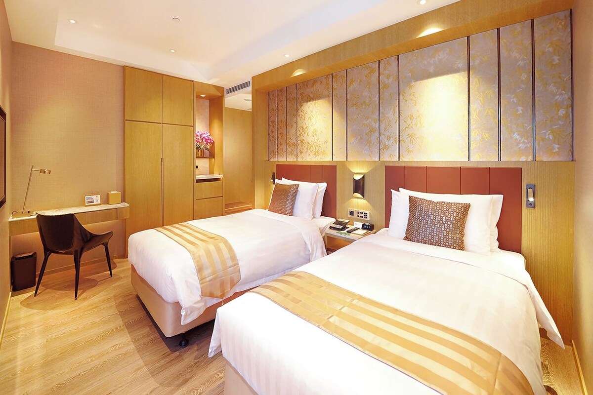 A hotel room with two beds, a desk, and a chair.
