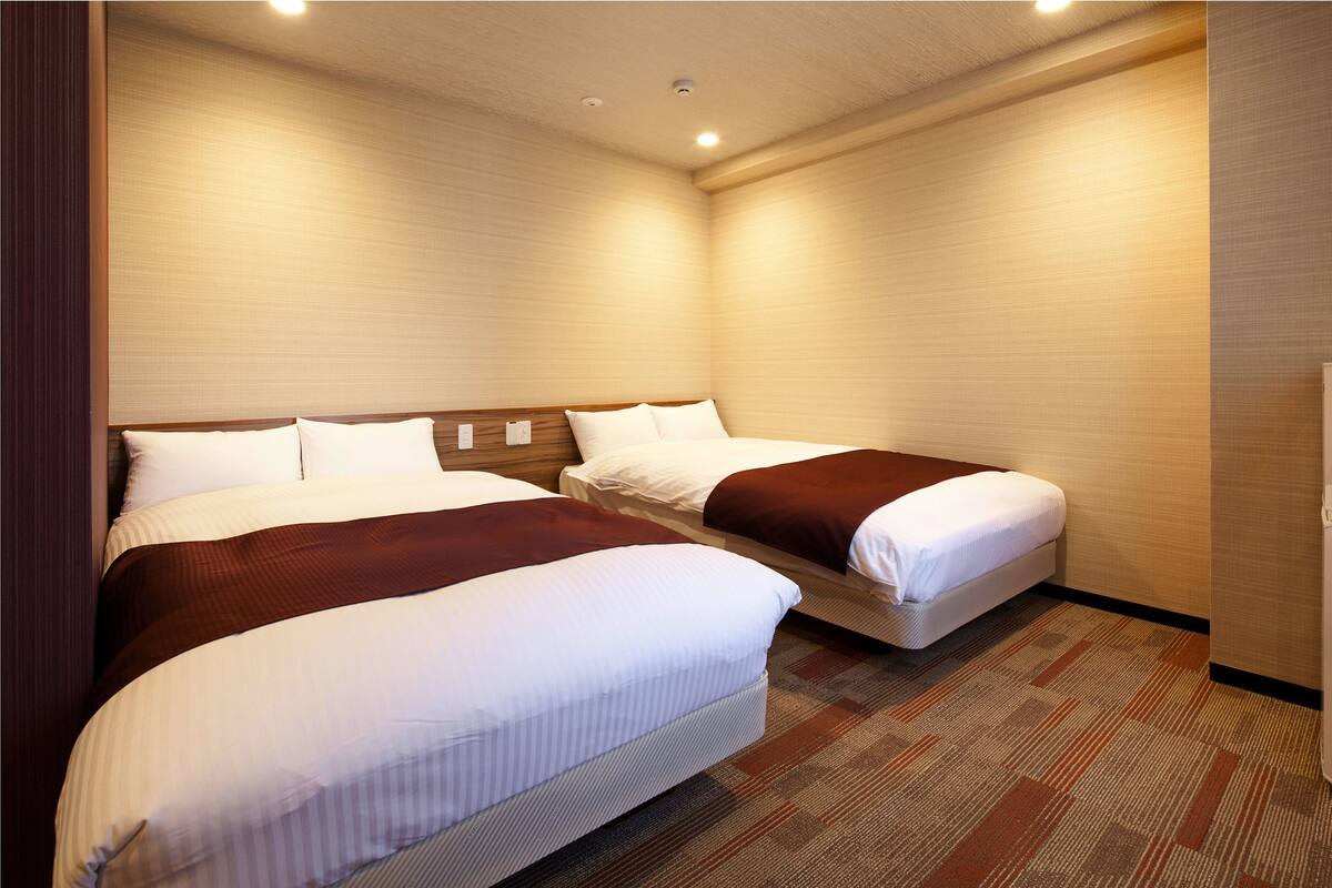Een hotelkamer met twee bedden, een vloerbedekking en een houten hoofdbord.