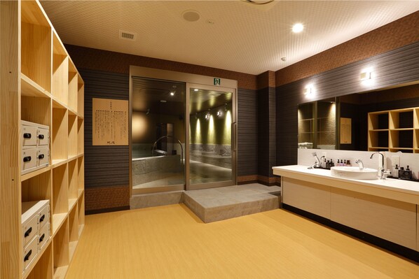 Un baño moderno con un espejo grande, un lavamanos y estantes de madera.