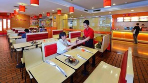 Un restaurante con cabinas y mesas, una barra y una pantalla de menú.