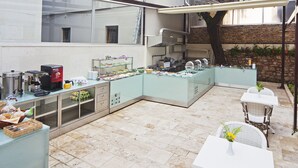 Un espace cuisine aménagé avec un buffet, comprenant une machine à café, un présentoir pour les aliments et un coin repas avec des tables et des chaises.