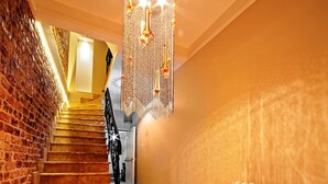 Un escalier dont le sol est recouvert d’un motif à carreaux, un mur de briques d’un côté et un radiateur de l’autre.