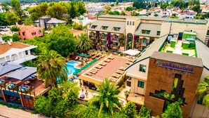 A hotel with a rooftop pool, outdoor seating, and lush greenery. - Ambassador Plaza (Kemer)