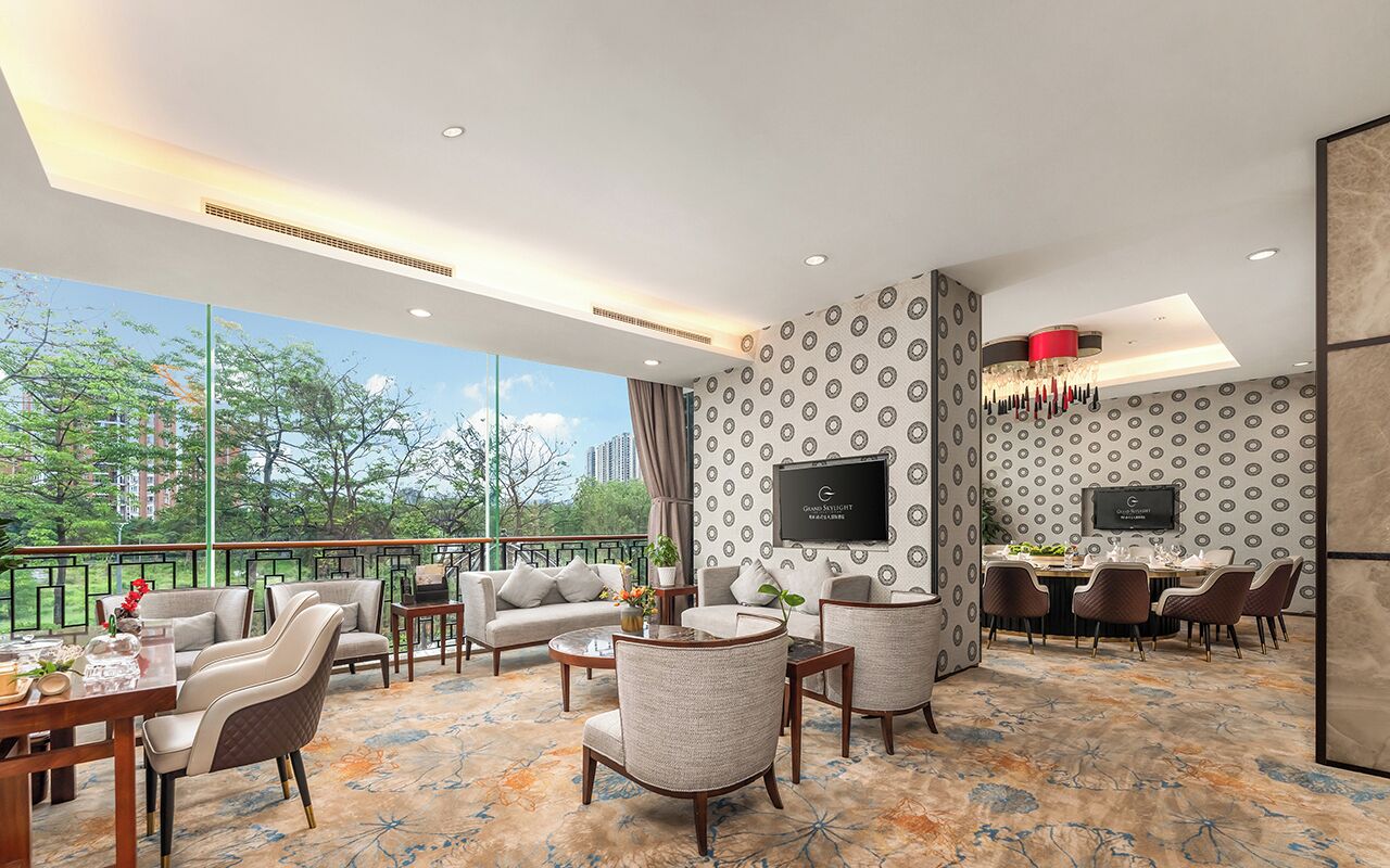 A modern hotel room with a balcony, a dining area, and a TV mounted on the wall.