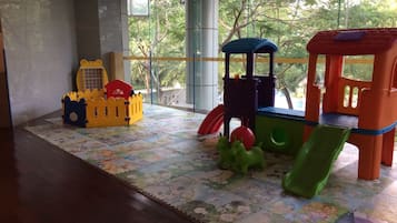 Children can play and explore in this room's play area, featuring a castle, playhouse, and vehicle.