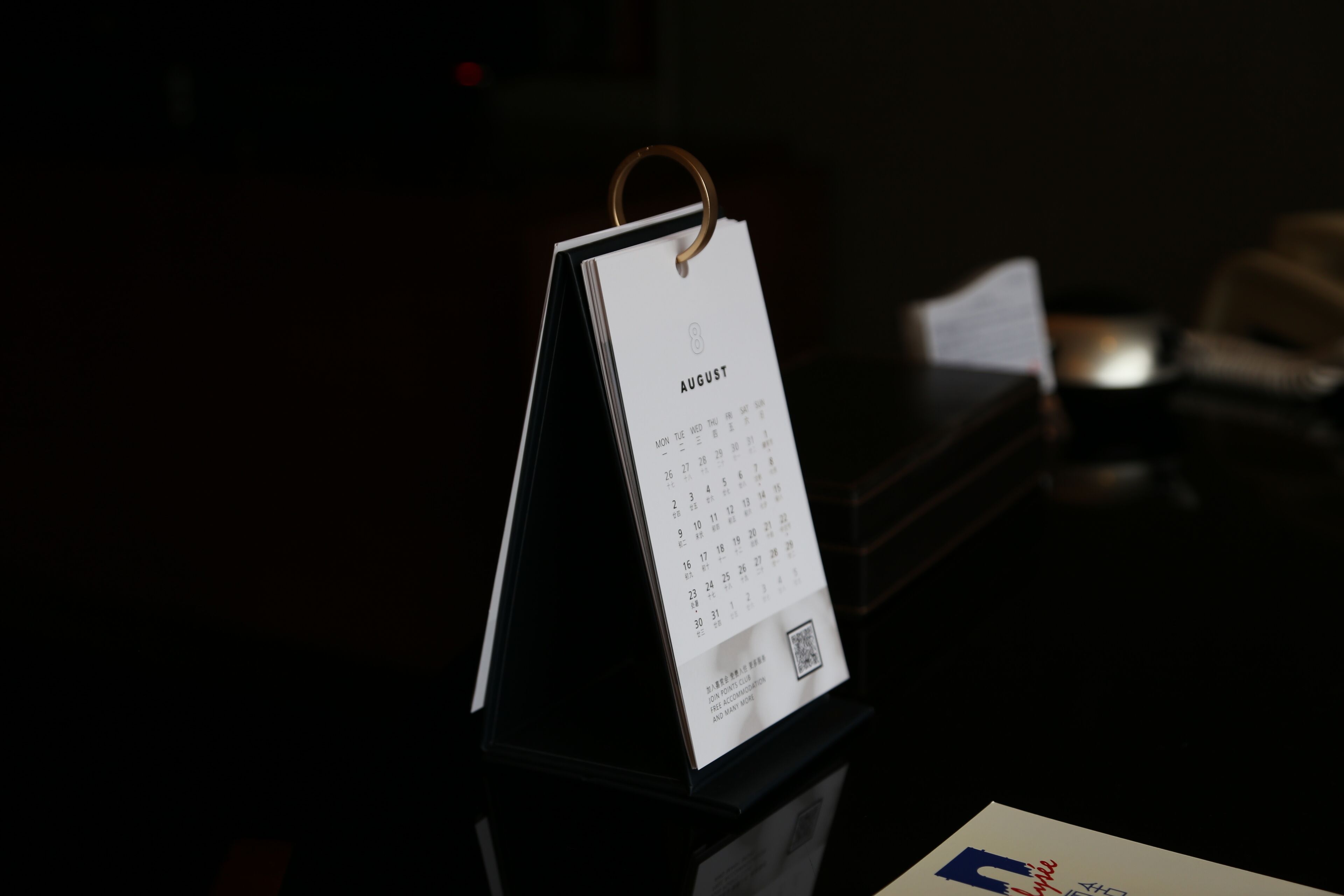 A calendar stand with a white calendar displaying the month of August.