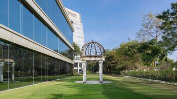 Un edificio moderno con fachada de vidrio y un jardín central con un pabellón.