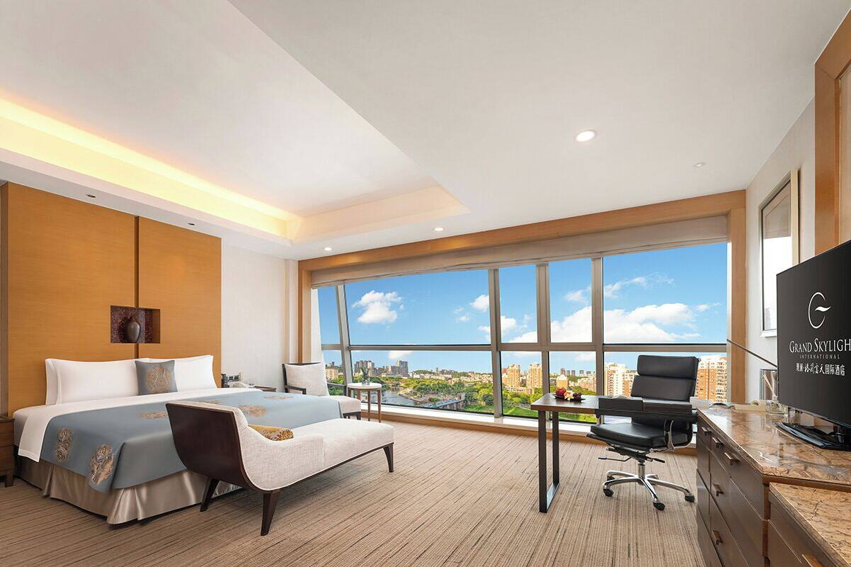 Moderni hotellihuone, jossa on suuri sänky, työpöytä, tuoli ja televisio.