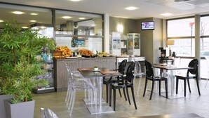 A modern restaurant interior with a counter, seating area, and a television screen. - Nemea Appart’Hotel Toulouse Constellation (Toulouse)