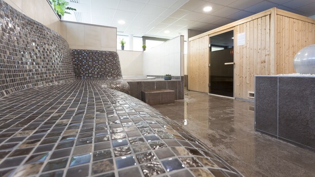 A modern spa area with a mosaic-tiled bench, wooden sauna, and a tiled floor. - Nemea Appart’Hotel Toulouse Constellation (Toulouse)