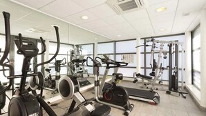 A gym with various exercise equipment, large windows, and a tiled floor. - Nemea Appart’Hotel Toulouse Constellation (Toulouse)