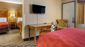 A hotel room with two beds, a desk, a chair, a TV, and a door.