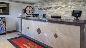 A reception desk with a clock, a digital payment terminal, and a magazine rack.