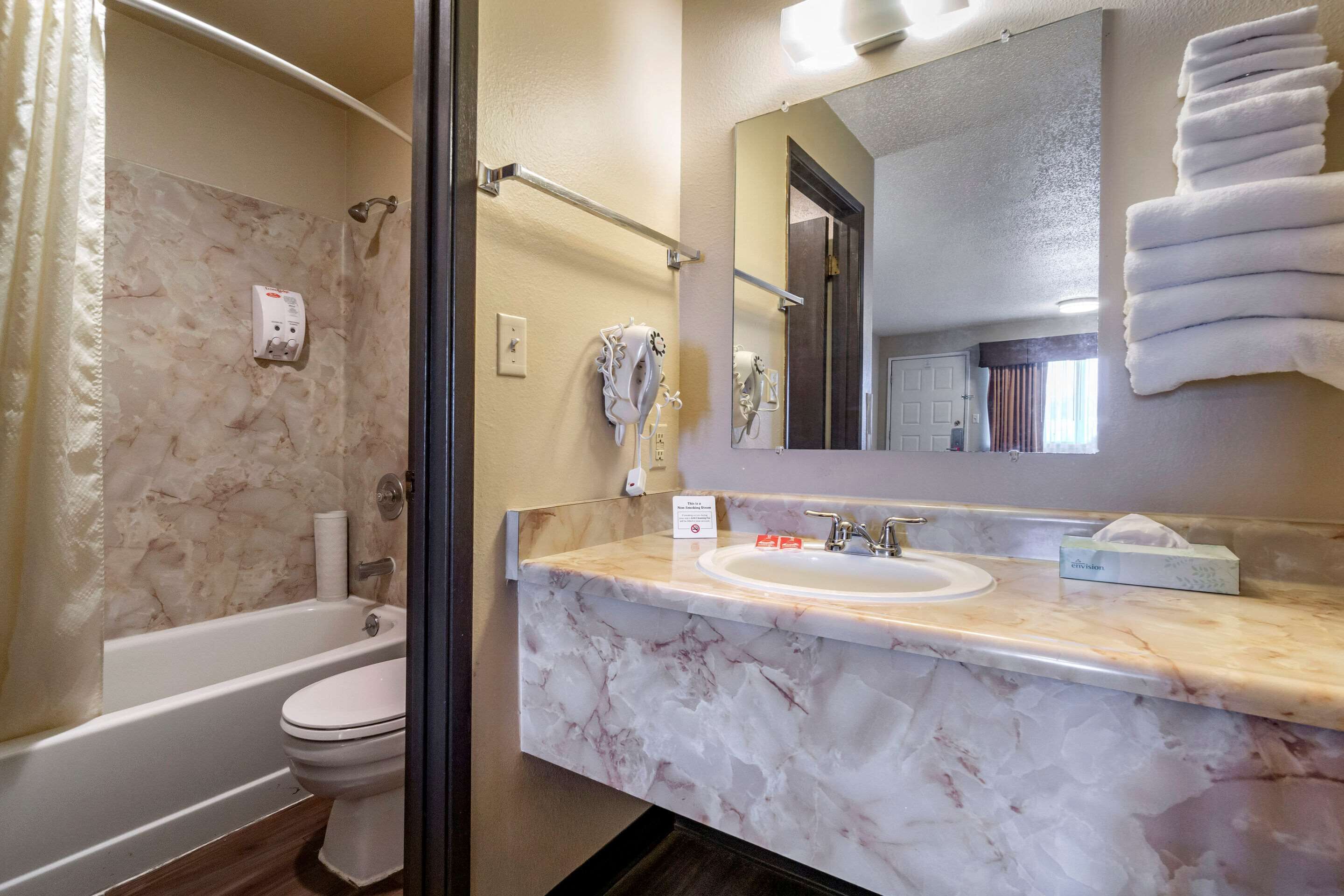 A bathroom with a marble sink, a bathtub, a toilet, and a shower.