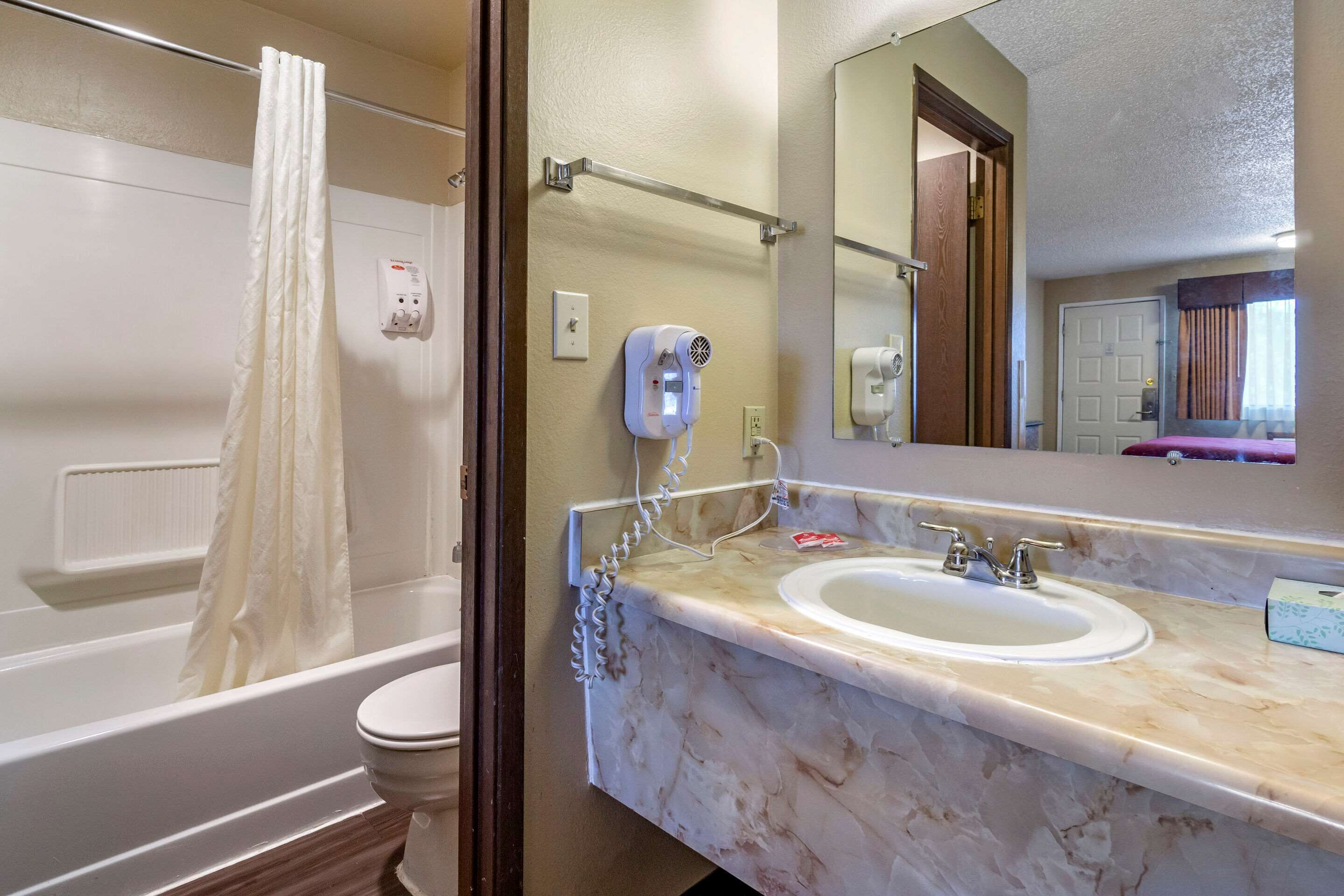 A bathroom with a bathtub, toilet, and a sink with a marble countertop.