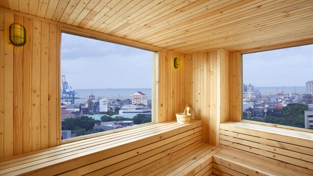 A wooden sauna with large windows offering a city view. - Hotel Santika Makassar (Makassar)