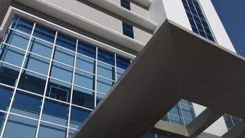 A modern hotel building with a prominent glass facade and a clear sky.