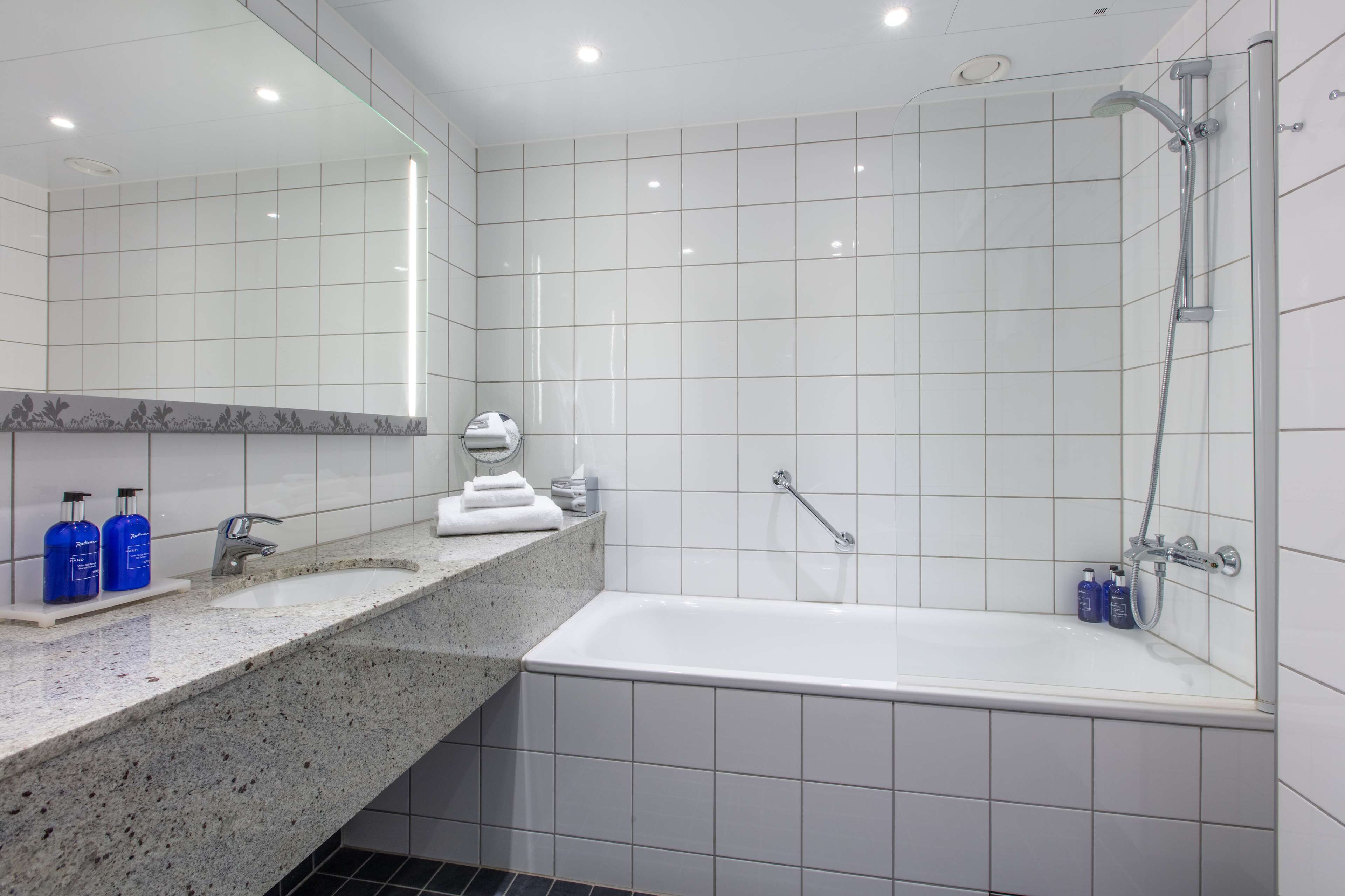 A modern bathroom with a large mirror, a bathtub, and a shower.
