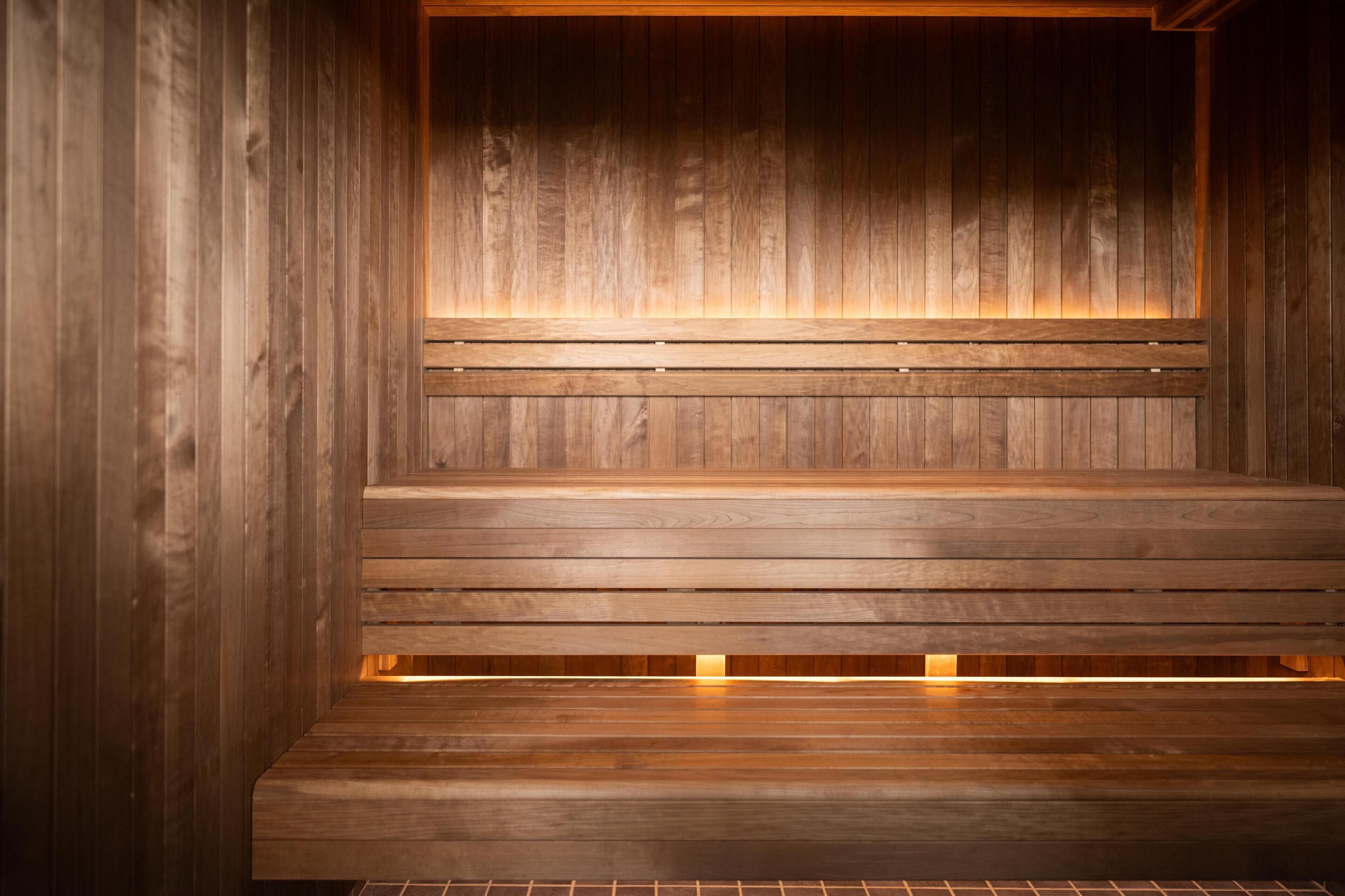 A wooden sauna with benches and a warm light source.