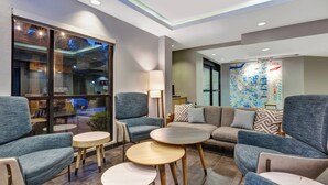 Un moderno vestíbulo de hotel con arreglos de asientos, un ventanal grande y un mapa en la pared.