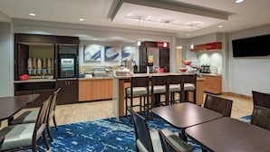 A modern hotel room with a dining area, kitchenette, and a TV mounted on the wall. - TownePlace Suites Monroe (Monroe)