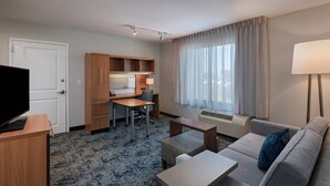 A hotel room with a desk, a sofa, a television, and a window with curtains. - TownePlace Suites Monroe (Monroe)