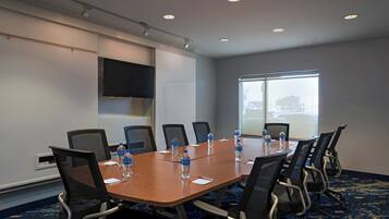 A conference room with a long table, eight chairs, and water bottles on the table.