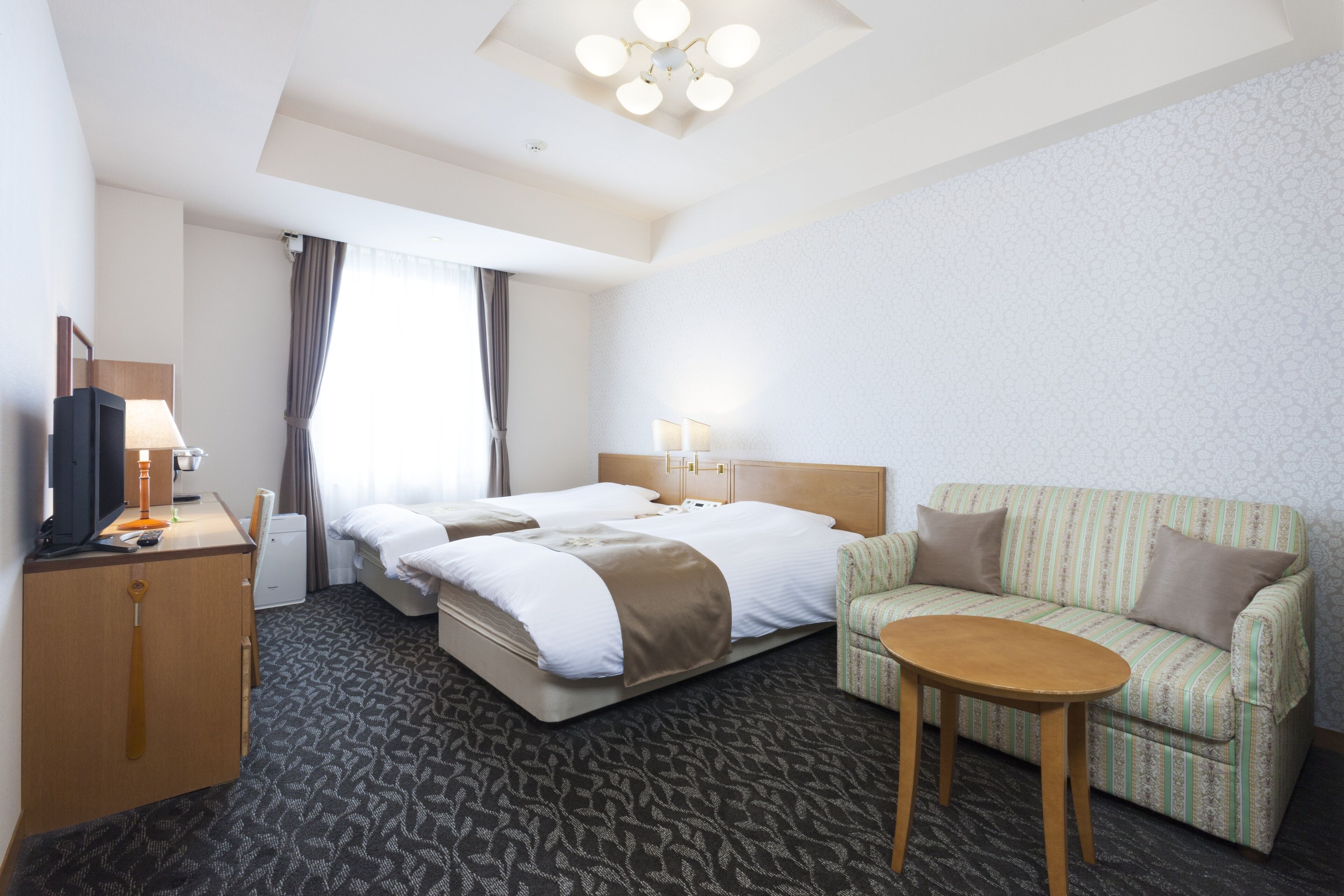 Una habitación de hotel con una cama grande, un sofá, una mesita y un televisor.