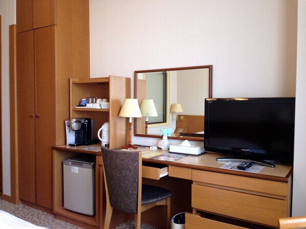 A hotel room with a wooden desk, a television, a mini-fridge, a chair, a mirror, and a small shelf with toiletries. - Hotel Nord Otaru (Otaru)