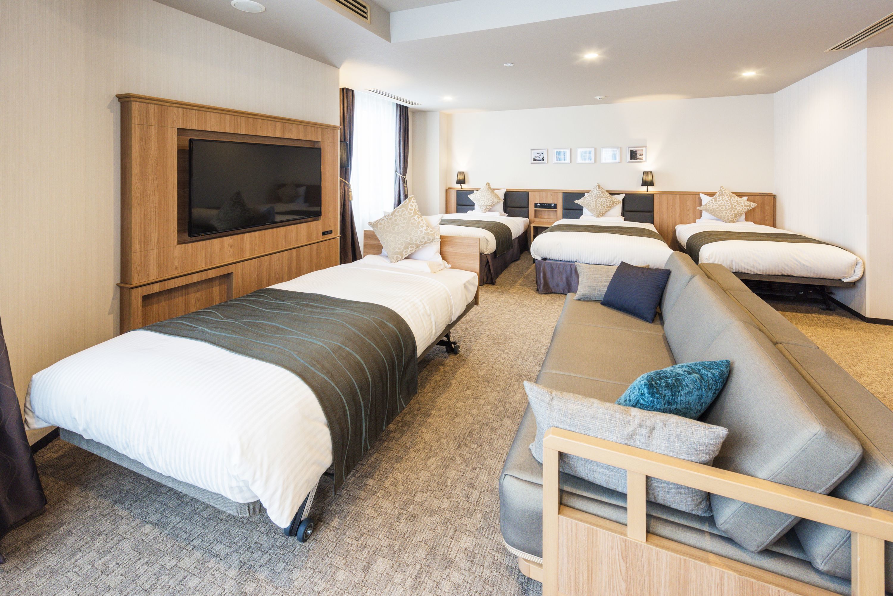 A hotel room with a large bed, a sofa, a TV, and a desk.