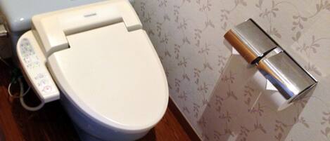 Un inodoro con panel de control y soporte para papel higiénico.