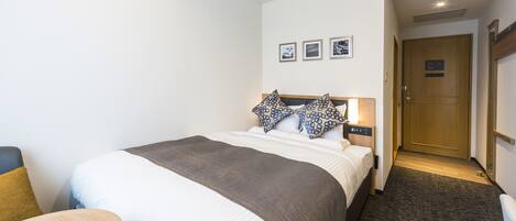 A hotel room with a large bed, a bedside table, and a door leading to another room.