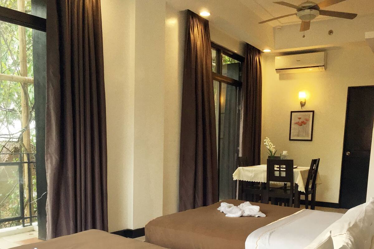 A hotel room with two beds, a desk, and a chair.